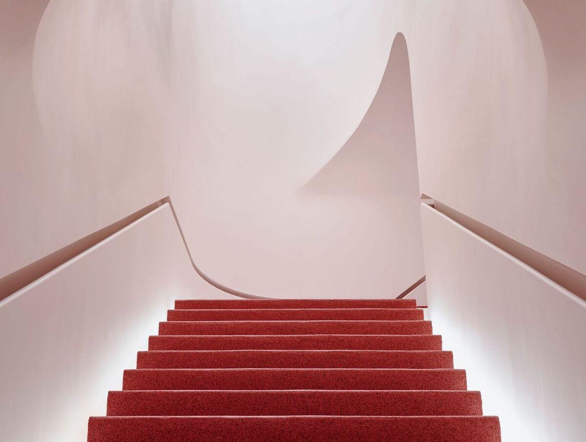 扶手裝嵌在樓梯兩側的牆壁上，樓梯蓋上紅色石英鵝卵石