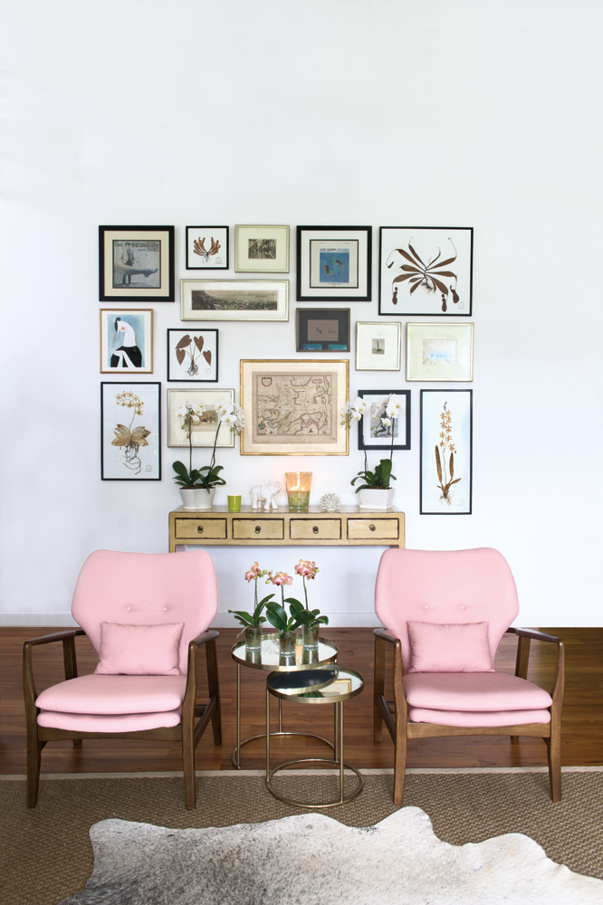 A pair of mid century-inspired chairs from Indigo Living upholstered by Albert Kwan from Wing Sun Upholstery frame the gallery wall perfectly.