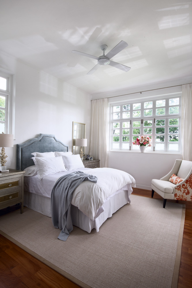 A muted cadet grey headboard sourced by Sasha Young Design structures the bedroom; distinctive Indian dressers bought shortly after the couple's engagement in India enjoy pride of place.