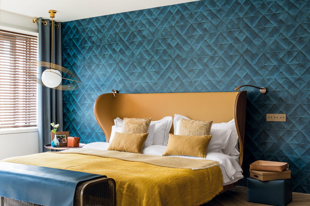 A quilted velvet wall in a rich ocean-blue marks the bedroom as a sanctuary of pure indulgence.