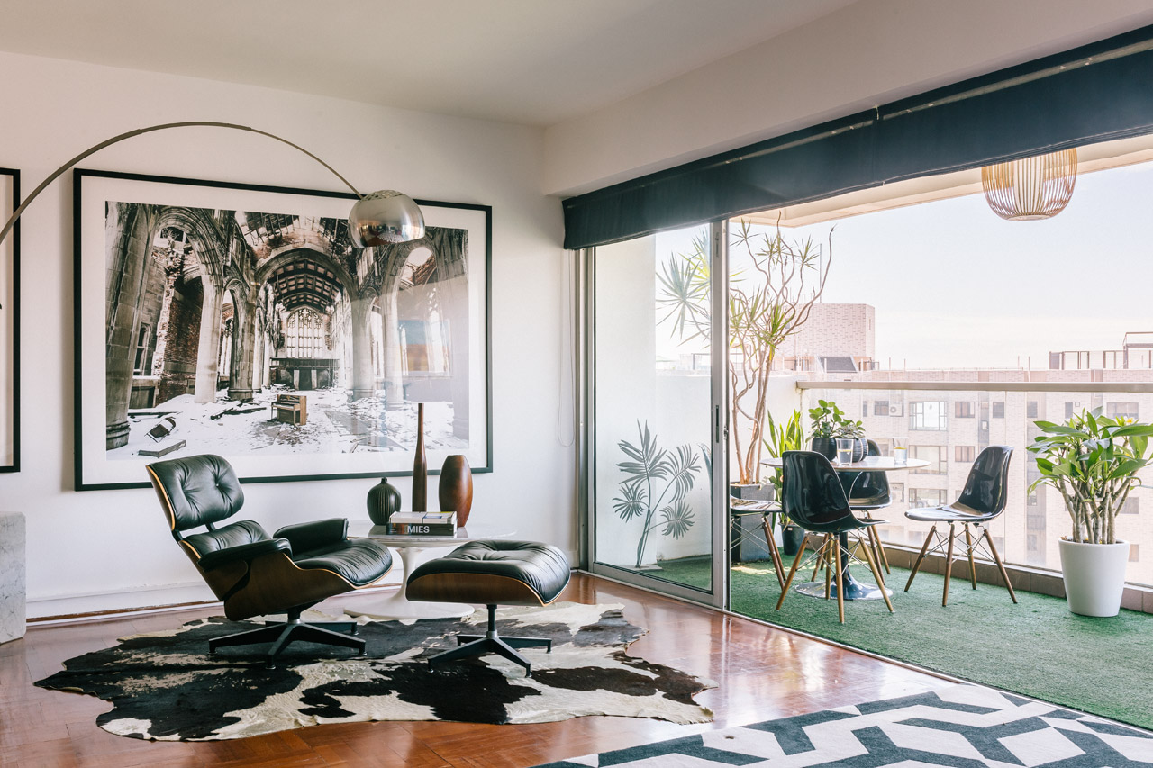 A striking photograph by Denice Hough and abstract artwork by Camie Lyons command the living room, beside an Achille Castiglioni Arco floor lamp.