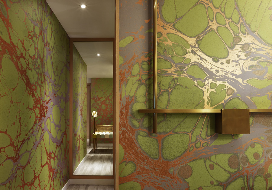 Marbled green wallpaper in the bathroom is reminiscent of trees in the summertime