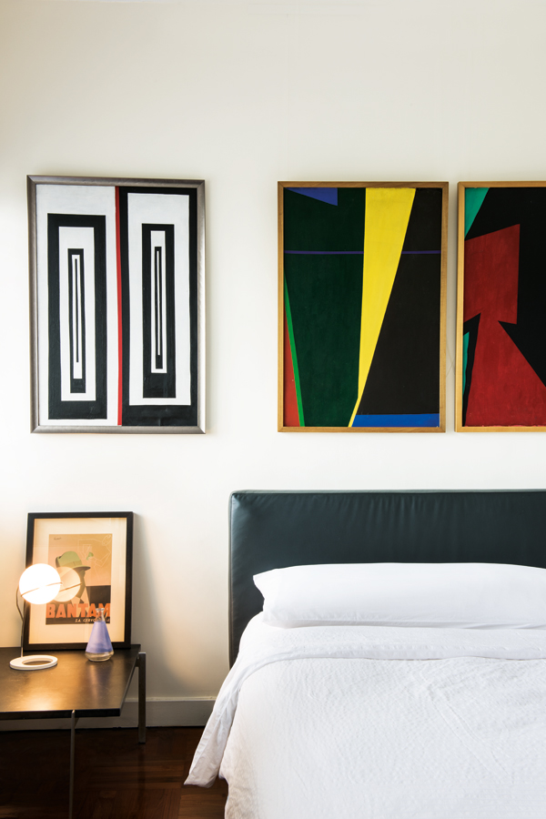 Three geometric oil paintings by Raskin, purchased from the St Sulpice antique fair in Paris, sit above the bed in the master bedroom