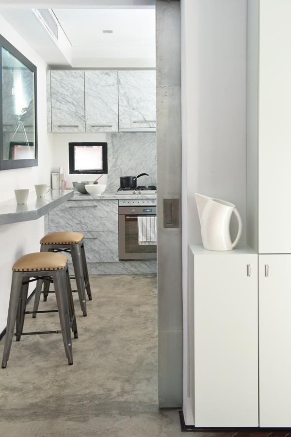 帶灰色紋理的Carrara大理石應用在廚櫃和拉絲鋁材早餐吧，兩者均為特製作品，為素色廚房奠下基調