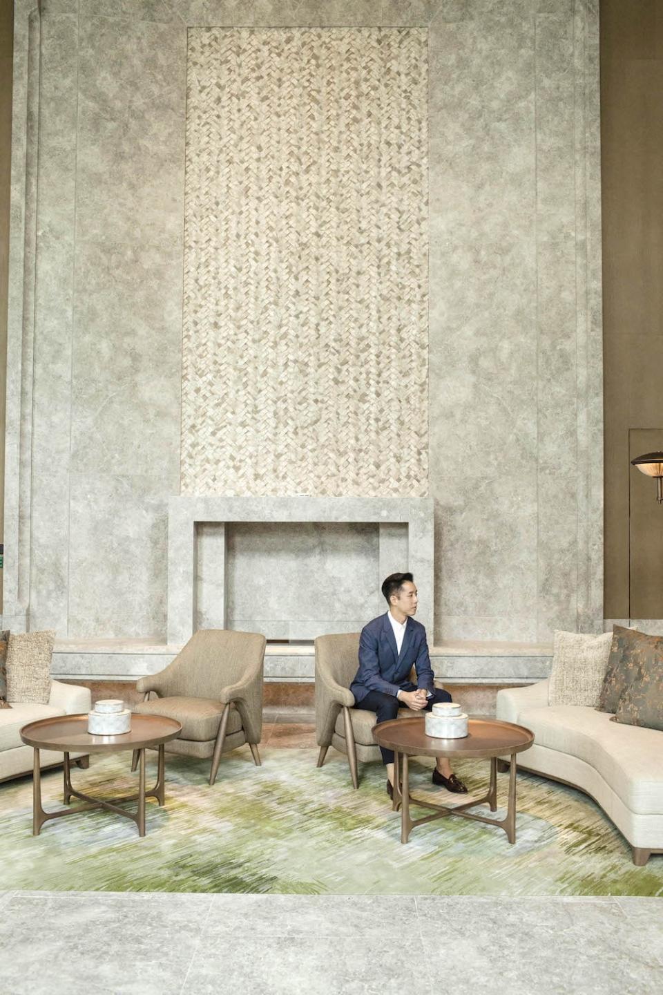 Andre Fu pictured against a soaring sculptural fireplace and AFSO’s Scenematic rug in moss green. Photo: Home Journal