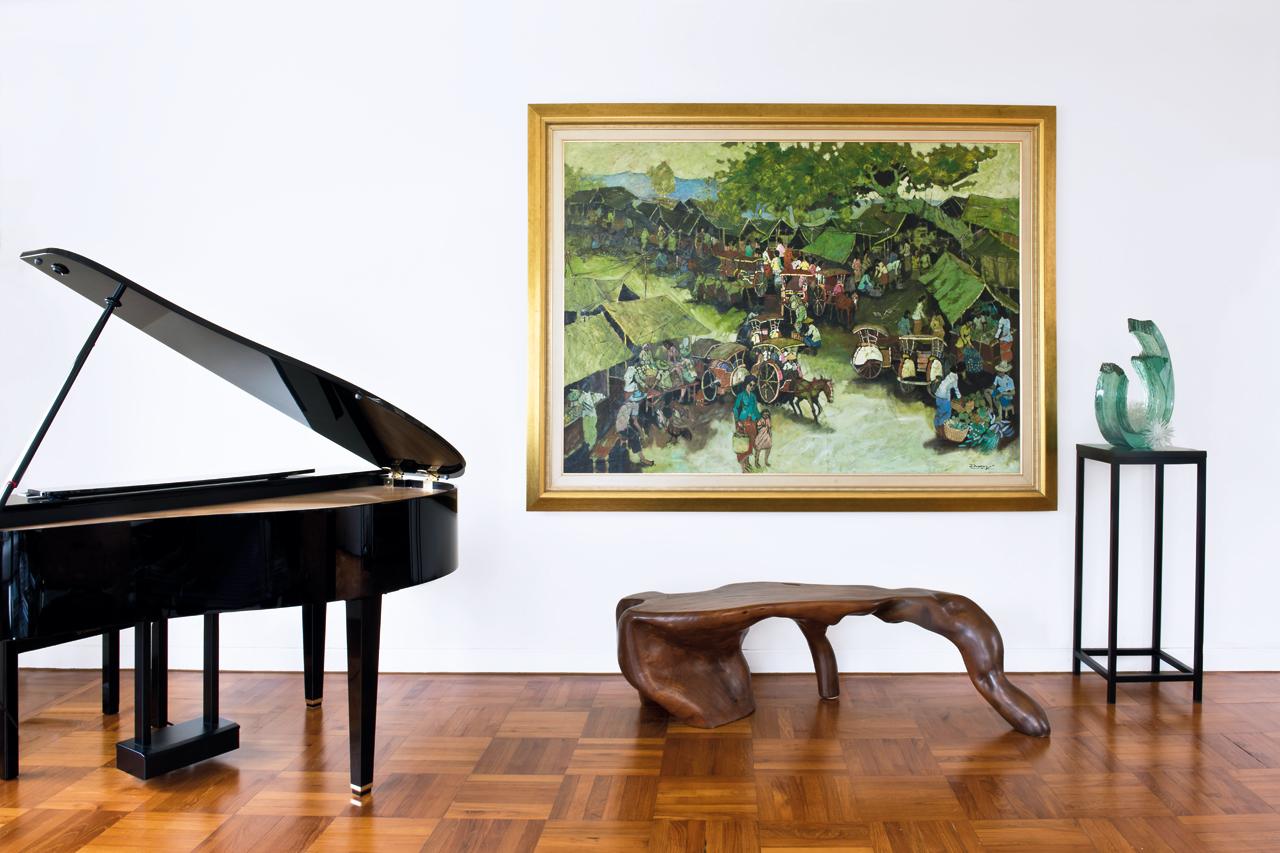 One side of the living room features treasured pieces – a large painting depicting a market, a glass sculpture and a grand piano. 