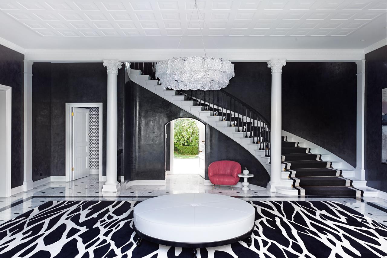 The flooring and the stairs of the entrance are in Carrara marble, offset by a striking black and white rug from Designer Rugs and the statement Rock Edge chandelier by John Pomp from A. Rudin