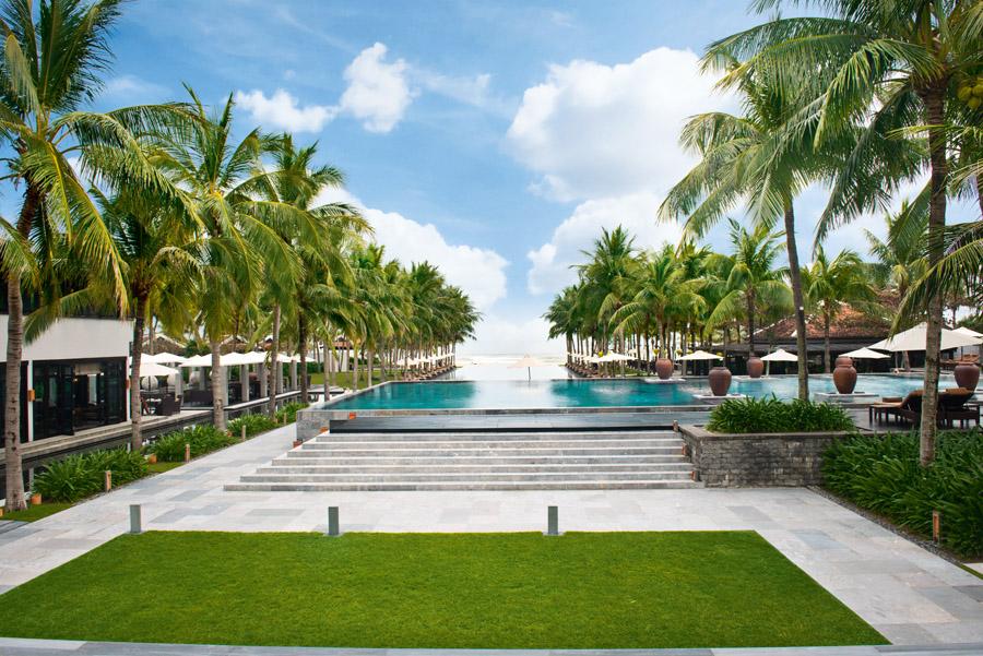 別墅的私人大泳池伴著草地而建，種滿棕櫚樹，並望向私人沙灘