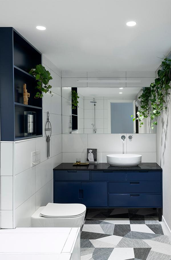 In one of the bathrooms, geometric floor tiles and dark blue shelvings further the home's modern aesthetic