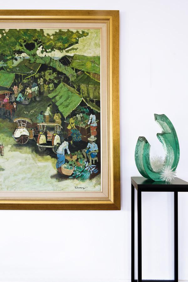 One side of the living room features treasured pieces – a large painting depicting a market and a glass sculpture