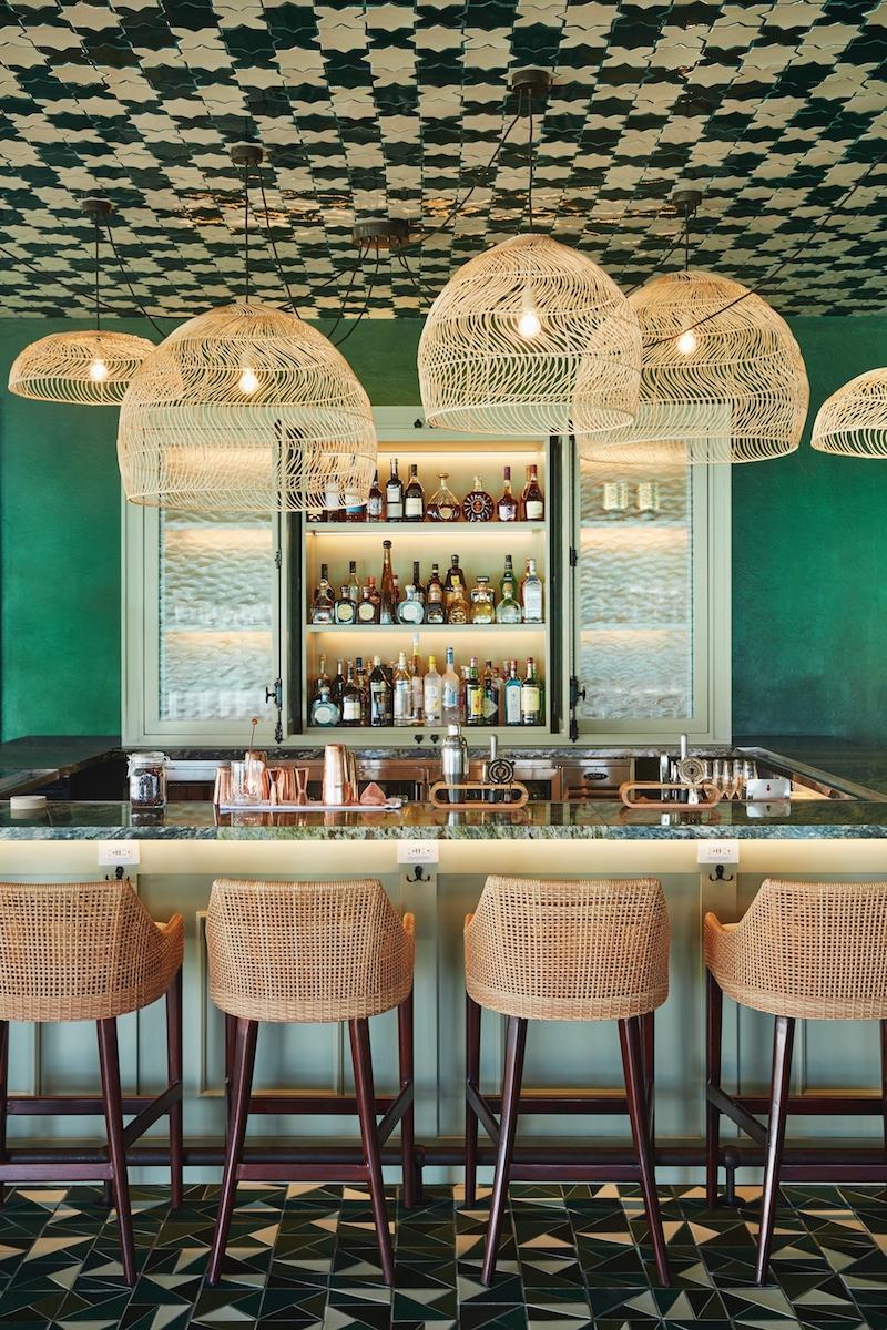 Deep green and white ceilings and tiles, punctuated by flashes of botanical prints and rattan accents, form the restaurant’s striking design