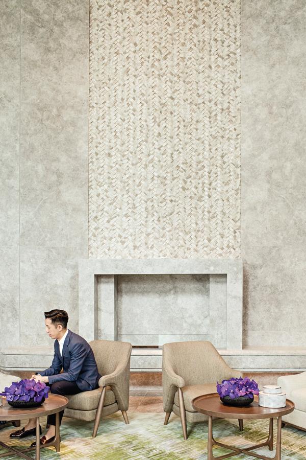André pictured against a soaring sculptural fireplace and AFSO’s Scenematic rug in moss green