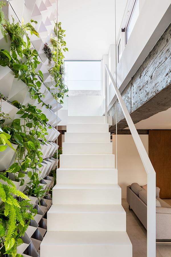Exposed concrete lend the loft a rustic, gritty feel, softened by the predominantly white interiors and the green wall's added touch of nature. (Photo: Kyungsub Shin)