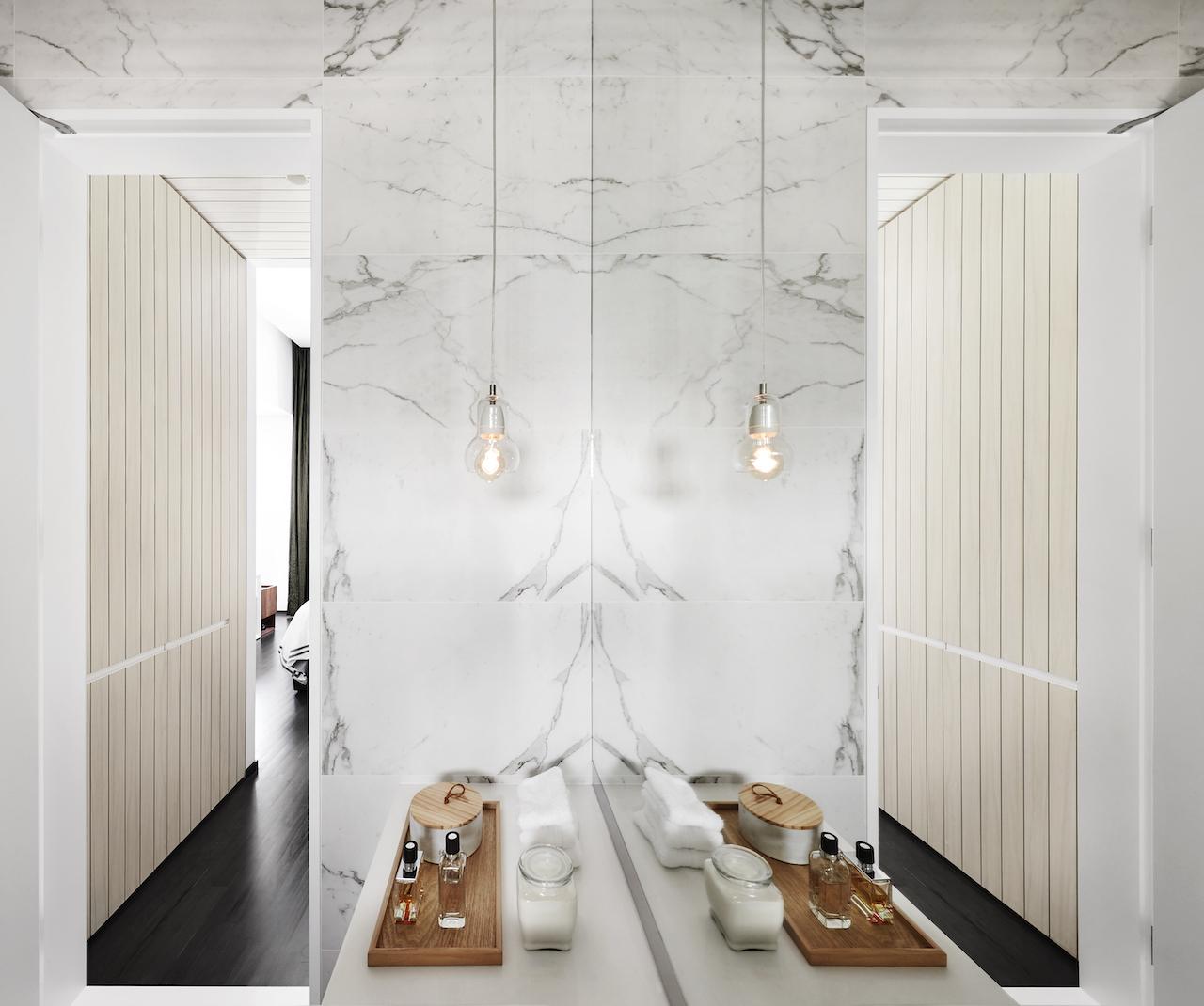 In the master bathroom, a pendant lamp from &Tradition complements white marble walls and floors