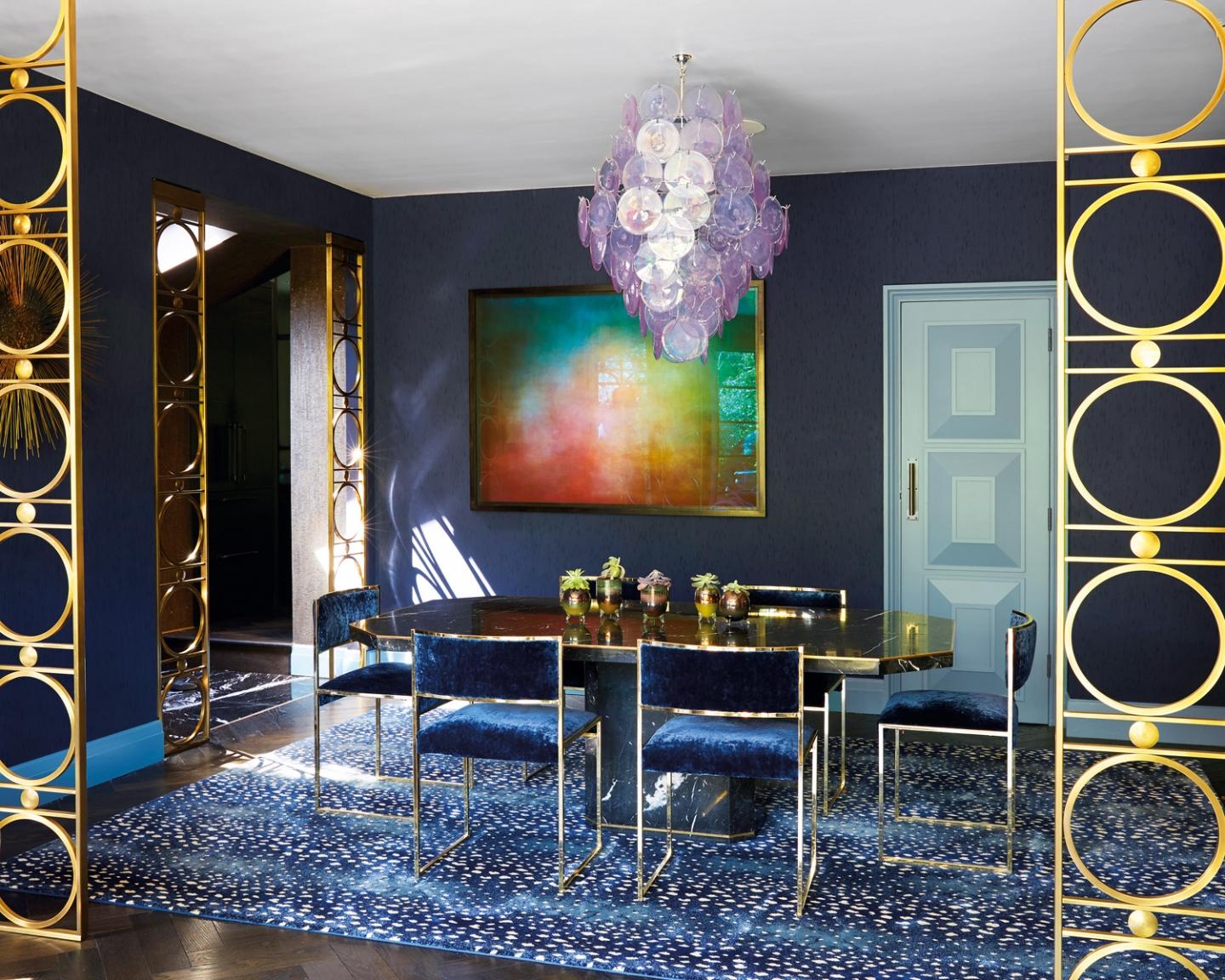 The dining room is an excercise in controlled contrasts, where a black marble table by Willy Rizzo intermingles with vintage chairs by Milo Baughman, a rug by Starck Carpets, a lilac disc chandelier by Vistosi and an artpiece by Jason Shulman