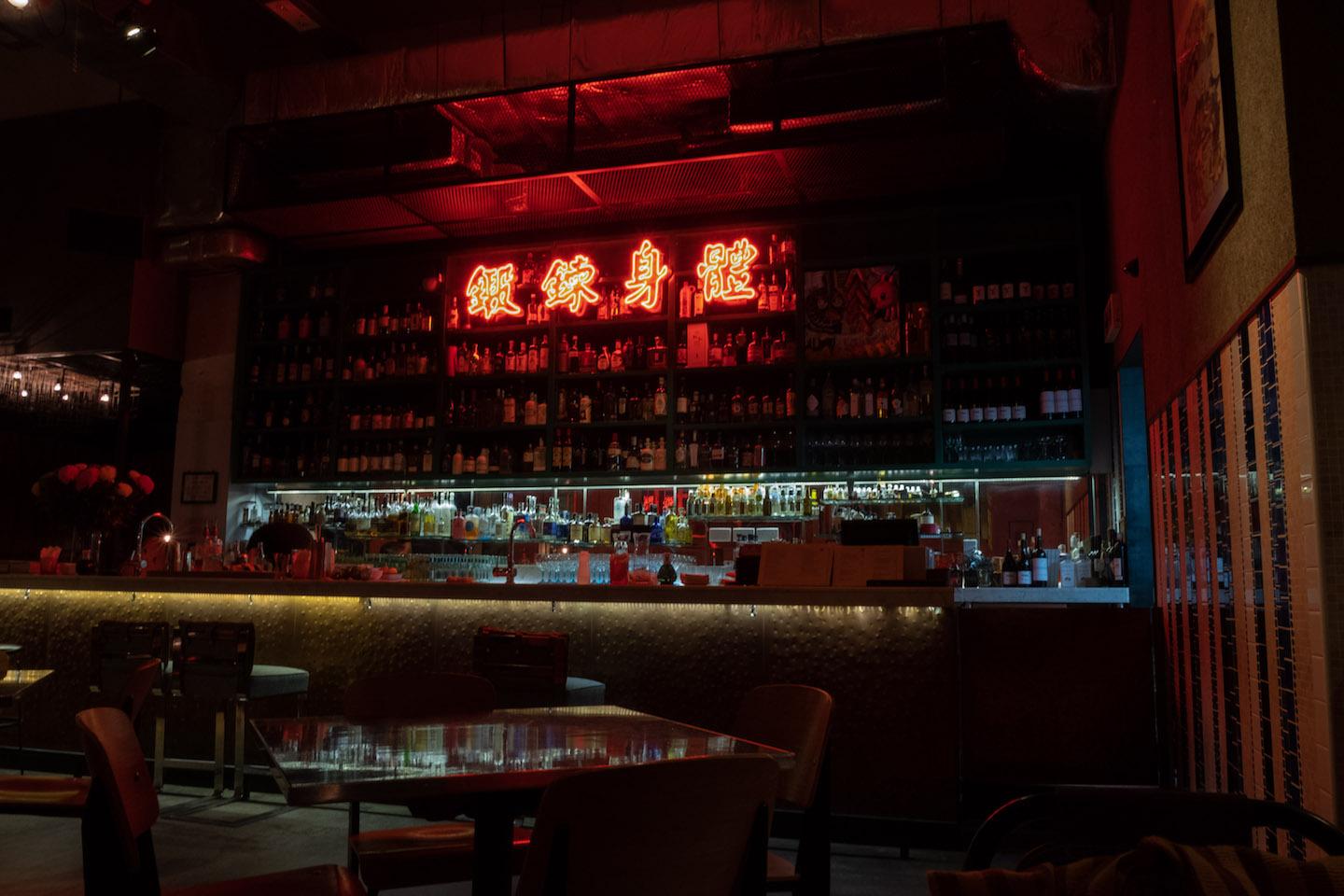 A red neon sign above the bar at Ping Pong 129 bathes the space in an ambient glow. Photo: Julian Morado