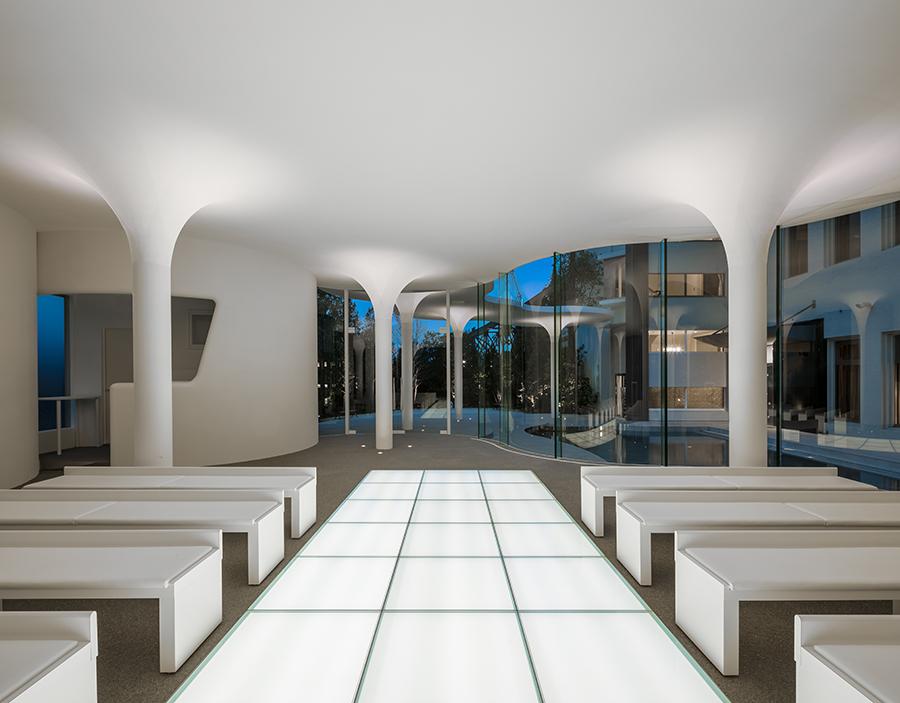 As well as the curved glass enclosure, the chapel's columns likewise feature curved details in connecting fluidly to the ceiling above. (Photo: Stirling Elmendorf, courtesy of KTX archiLAB)