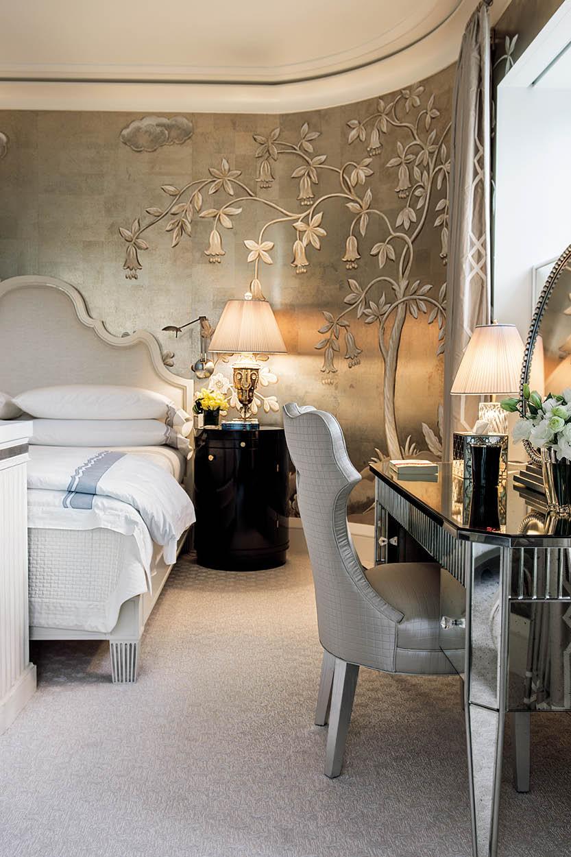 A bedroom with hand-painted wallpaper. “With curved corners, the master bedroom has a wonderful sense of enveloping embrace. Covering the walls in silver tea paper from Gracie infused the interior with an almost art deco allure…” (Photography by Paul Costello)
