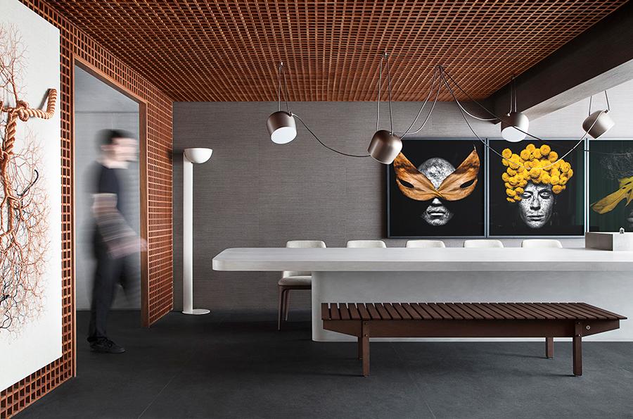 Above the Corian dining table-bar, the Aim suspension lamp by Flos. Wall portraits are by São Paolo photographer, Gabriel Wickbold. (Photo: Courtesy of Studio Guilherme Torres)