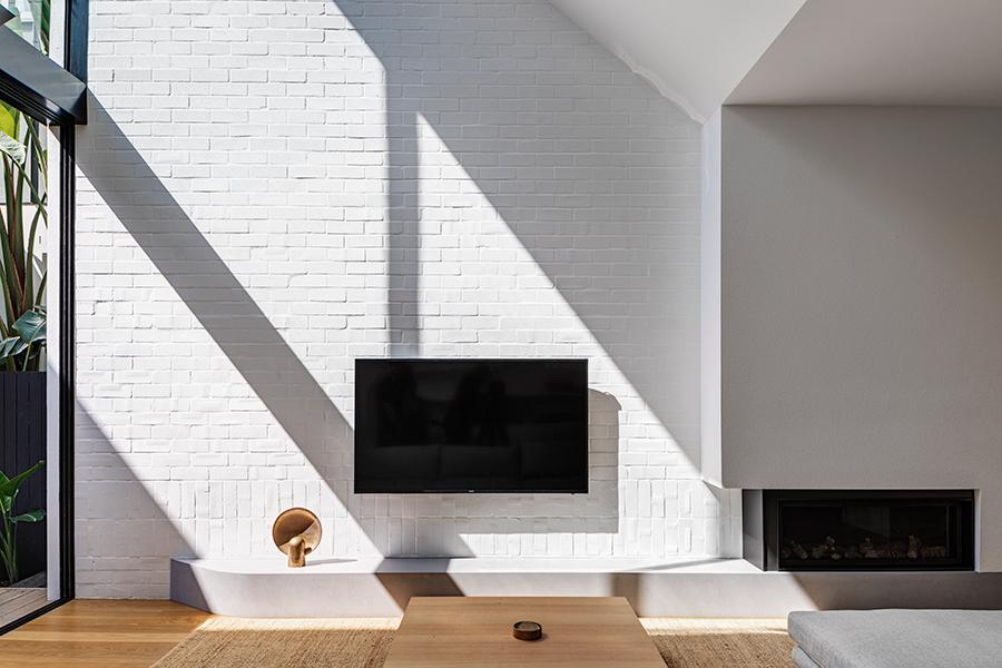 A white brick texture wall adds character to the living room on the ground level. (Photo: Murray Fredericks, courtesy of Akin Atelier)