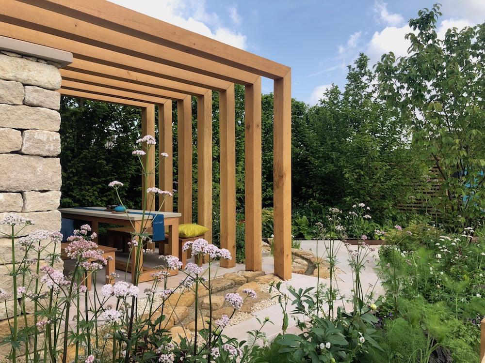 Verdant flora surrounds a wooden beamed sitting area