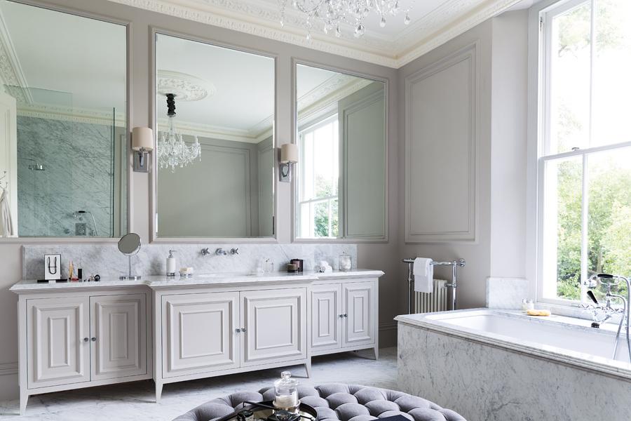 Three mirror panels above the freestanding vanity accentuate the symmetry of the opulent master bathroom