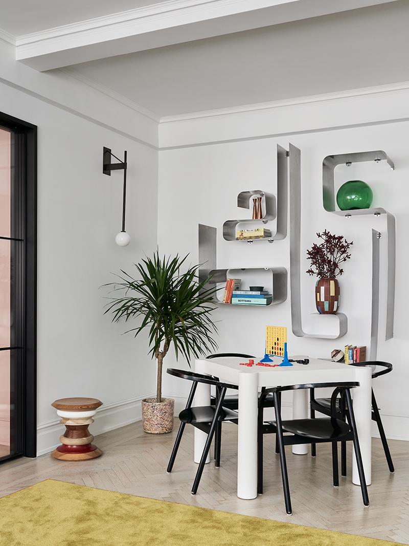 Across the living room's sitting area, a sculptural stainless steel shelving unit by Francois Monnet, next to a game table. (Photo: Brooke Holm)