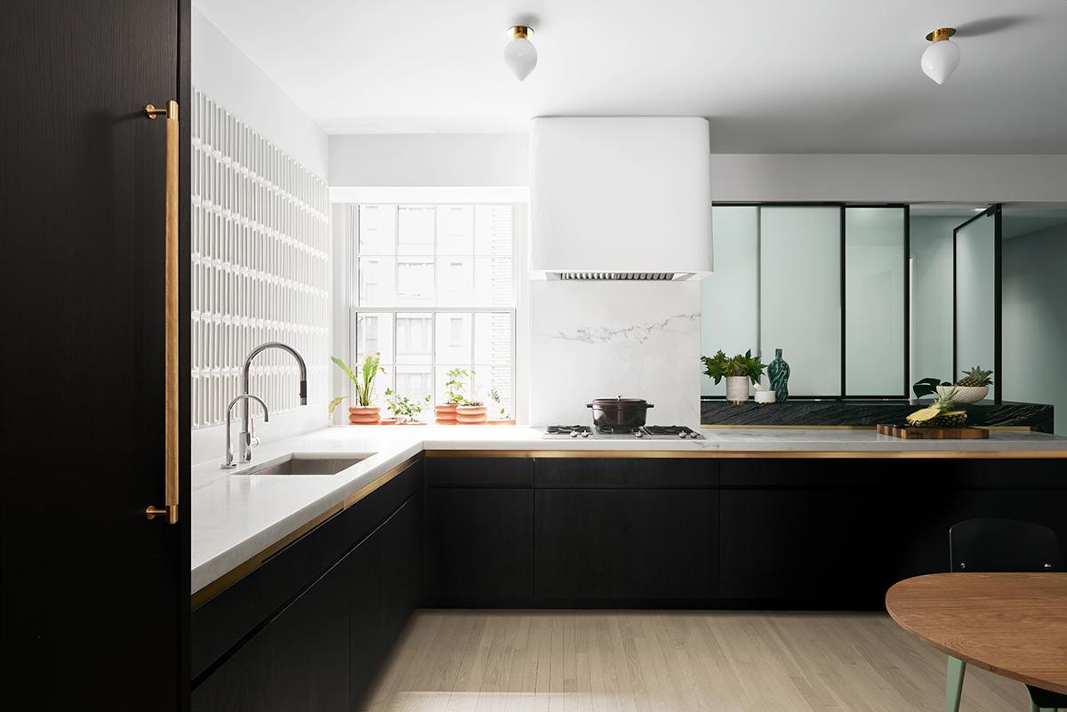 A lacquer and ebonised oak pantry links a smaller dining room and kitchen, which feature three-dimensional tiles from Ann Sacks and a pale wall covering from Flat Vernacular. Beneath the glass partition is a counter made of striped Kenya black marble. (Photo: Brooke Holm)