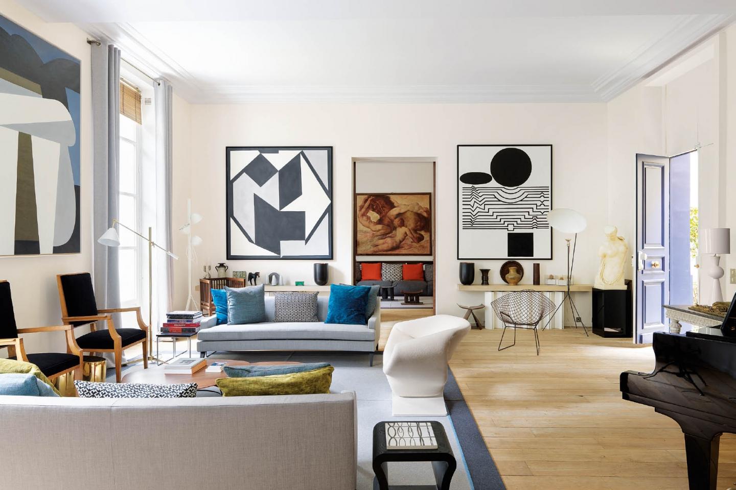 Chairs and cushions add pops of colour in the living room, but the focus is squarely on the artworks; the grand piano is reminiscent of Didier Gomez's musical study. Gomez endeavored to introduce more vivid colours into his home's new design