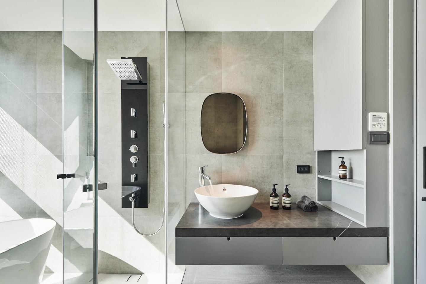 質感豐富的牆磚、圓鏡和小巧的洗臉盆，讓洗手間更顯精緻細膩